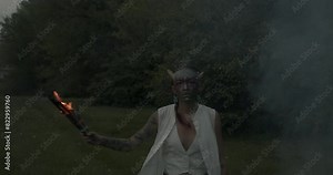 Beltane festival, a Scottish tradition, a participant blends ancient customs with contemporary artistic expression. Holding burning firewood, embodying a mythological figure, ignites the festivities.