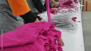 Quality control of garments in textile factory. Workers in the process of packaging textile products