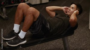 4k Asian man doing abdominal exercise on the black bench at the gym, evening body weight training, strong, weight exercise, workout, side view, core strength, abs crunch, six pack workout routine