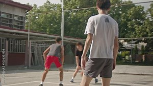 Friends playing basketball at an old schoolyard court. A group of high school boys enjoys their free time playing street basketball.
