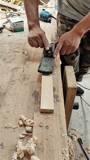 Hands Adjusting a Hand Plane to Smooth a Piece of Wood on a Workbench