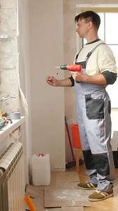 Download A man in overalls is holding a drill for free