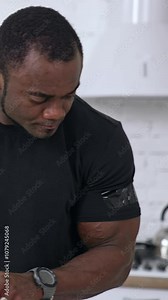 Healthy african man in the kitchen. Handsome black man in black t-shirt with muscular body cooking food with fresh vegetables. Vertical video