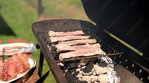 bacon strips grilling over hot coals on a sunny day raw bacon ready for the grill showcasing start-to-finish process of cooking bacon outdoors smoky aroma combine to create a perfect barbecue ambiance