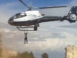 Bizarre footage shows a man hanging onto flying helicopter
