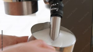 Barista steaming milk in a pitcher. Wife whips milk with steam in a pitcher at home