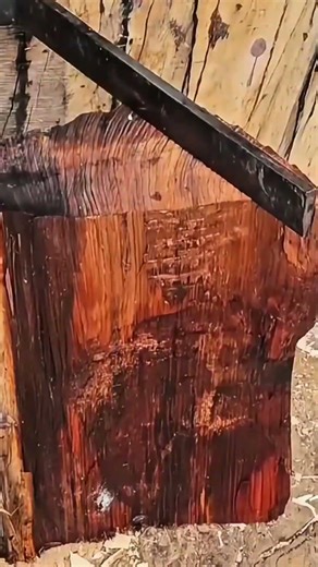 splitting a thick block of dark wood using a froe and a large wooden mallet for traditional crafting