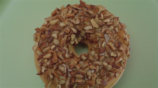 Donut with nut rotating on a pastel green background - Free Stock Video