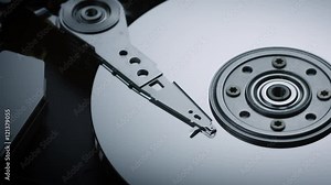 rotating dolly macro shot zoom in of the inside of a modern computer hard disk drive with moving actuator arm reading and writing data from the platters