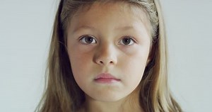 Close up of a little girl (kid) face while she is looking in the camera on white background.Shot with RED camera in 8K. Concept of childhood, kids protection, daughter, happy family