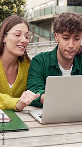 Two students working together on a laptop, studying and learning for University exams