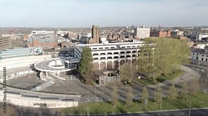 Covid virus suburban town lock down aerial view over quarantined British retail buildings and multi storey car park ascending