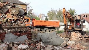 Excavator demolish and cleaning old house, loading dump truck, wide angle shot.