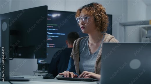 Concentrated Asian AI Programmer and Machine Learning Developer Focused on Screen, Writing code, Working on website development, software developing project in software company office.