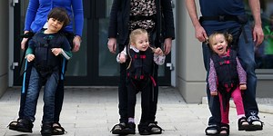 Crutches that are attached to the legs of adults, for children who do not walk (Video)