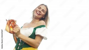 A beautiful dancing girl dressed in Oktoberfest costume of Bavaria holds a beer mug and a traditional Bavarian pretzel. The woman leans over the camera, the bottom view. Dance to Oktoberfest