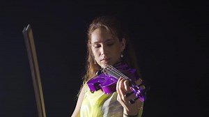 Female violinist playing the violin in the opera or dark music hall. Classical Musics. Talented violinist woman plays classical music with her violin. Music and art.