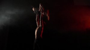 A man holds a girl with one hand, acro yoga in the dark. Slow motion