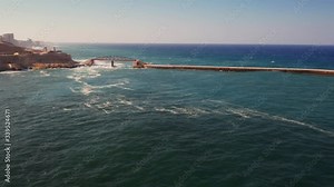 Aerial view of big waves on the red Breakwater Bridge during stormy weather. Camera moves forward and turn. Valletta city, Malta island
