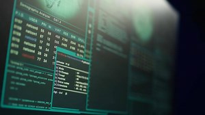 Close up shot of dangerous hacking code running on high tech computer system monitors. Programming scripts shown on PC displays in empty criminal hideout used by hackers to commit illegal activities