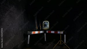 A dark tunnel is blocked by a barrier. Beyond the barrier, another tunnel is visible, its entrance illuminated by a focused flash light, adding depth underground expanse