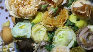 Someone cuts a piece of cake with a spoon. Baked goods are decorated with imitation flowers of roses and handmade Ranunculus. Cream floristry, real time, wedding cake, holiday, natural light, close-up