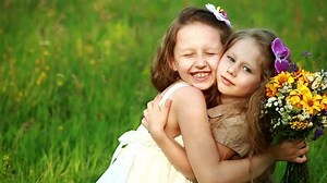 Sisters hugging while sitting in the grass