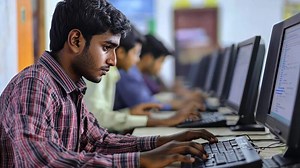 Download A man is sitting at a computer in front of other people for free