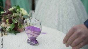 A wedding ceremony with a mixed family. The groom, mother, and son perform a unity sand ceremony mixing each of their colors into one beautiful piece of art.
