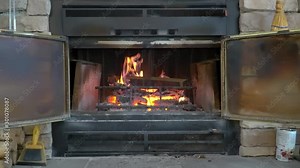 Slow burning logs In a vintage brick fireplace with screen in front of the fire. Close up and Zoom out