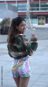 young man walking backwards, turns to look into the camera and tells you to come