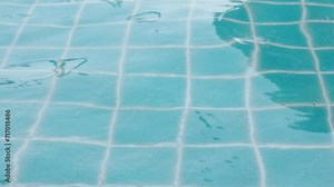 Close up water surface in the swimming pool with blue tile on the bottom shows beautiful wavy and rippled water with glitter and shiny reflection of sunlight on clear and clean water.