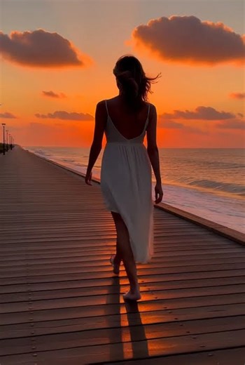 Woman Walking on a Seaside Boardwalk at Sunset