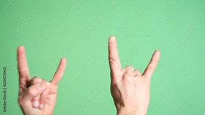 Hands gesturing heavy metal rock sign isolated green screen