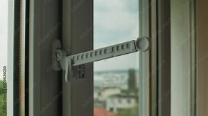 Master installed fixing limiter for opening plastic window and checks its operation. Close-up of hand in glove checking operation of window fittings. Home repairs. Installing window hardware