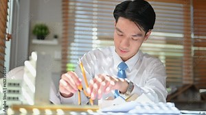 Civil engineer man using compass to measuring scale on a blueprint, working construction project in a creative office