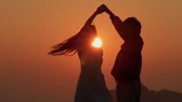 silhouette of couple in love celebrating life dancing in slow motion...
