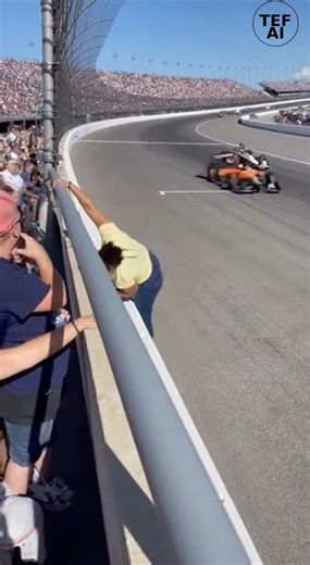 Spectator Loses Balance While Filming Speedway Race, Quickly Recovers Daytona Beach, Florida — February 16th, 2025 A tense moment unfolded during a motorsports event in Florida after a spectator briefly lost her balance while leaning over a protective ledge to film cars racing below. The incident, captured on nearby cellphone video, occurred as vehicles passed at speed on the track beneath the grandstand area. The footage shows the woman leaning forward with her phone extended when she suddenly 