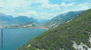 Breathtaking vista of Torbole, Lake Garda, amidst nature's splendor with towering rocks, expansive sky, and ever-changing clouds, offering an invigorating hiking adventure in Lomba