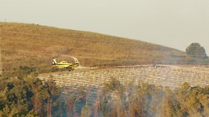Firefighter plane drops fire retardant on a forest fire in the hills - Free Stock Video