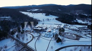 Sunset over snow blanketed hill sheltering a museum and arts complex among forests of hardwoods and evergreens. Located in Williamstown, Massachusetts, New England, United States