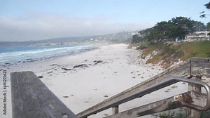 Ocean sandy beach, Carmel, Monterey nature, California coast USA. Big foamy sea water waves crashing on shore. Vacations waterfront beachfront resort. Sunny weather, wooden stairs, steps or stairway.