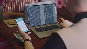 Trader Transferring Money to Bank Account Using Phone and Laptop