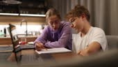 Sister and teenage brother doing some homework together. The sister...