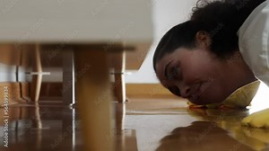 Professional cleaning service. Shocked household bends down to look under slit between sofa and floor and wipe with gloves a lot of dust. Low angle view from couch.