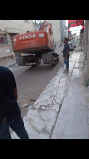 Excavator Lifts Concrete Slab at Urban Construction Site