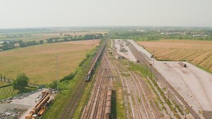 View of a freight train passing near warehouses and grasslands - Free Stock Video
