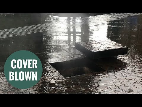 Terrifying moment a manhole cover "explodes" during flash floods