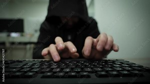 Unrecognizable man hacker wearing sweatshirt with hood typing on laptop computer keyboard and breaking password. hacker attack on servers. cyber crimes. focus on hands. searching for information