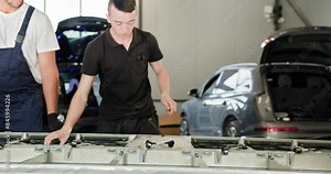Male Technician Inspecting And Troubleshooting An Electric Car Battery Module In A Modern Vehicle Repair Workshop. Engaged In Detailed Battery Repair And Maintenance. Electric Car Battery Handling.